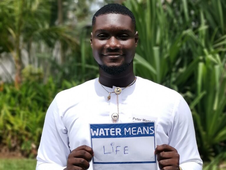 A male participant holding a sign stating "water means life"